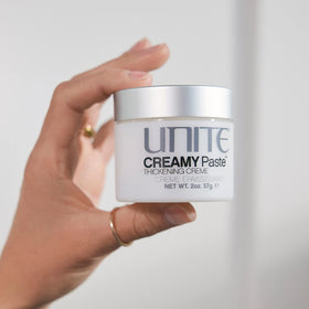 UNITE open jar in hand showing 2 oz size and travel-friendly benefit