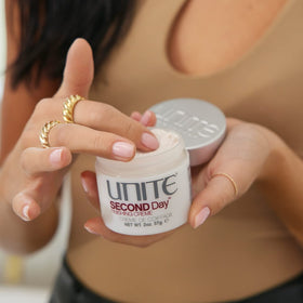 UNITE SECOND Day next to hairbrush for scale showing compact 2 oz size and travel convenience