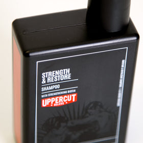 UPPERCUT DELUXE label close-up highlighting biotin and caffeine, clarifies key actives