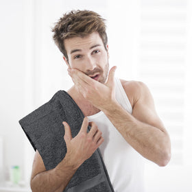Utopia Towels next to hand for scale showing 16x27 inch size clarity and fit
