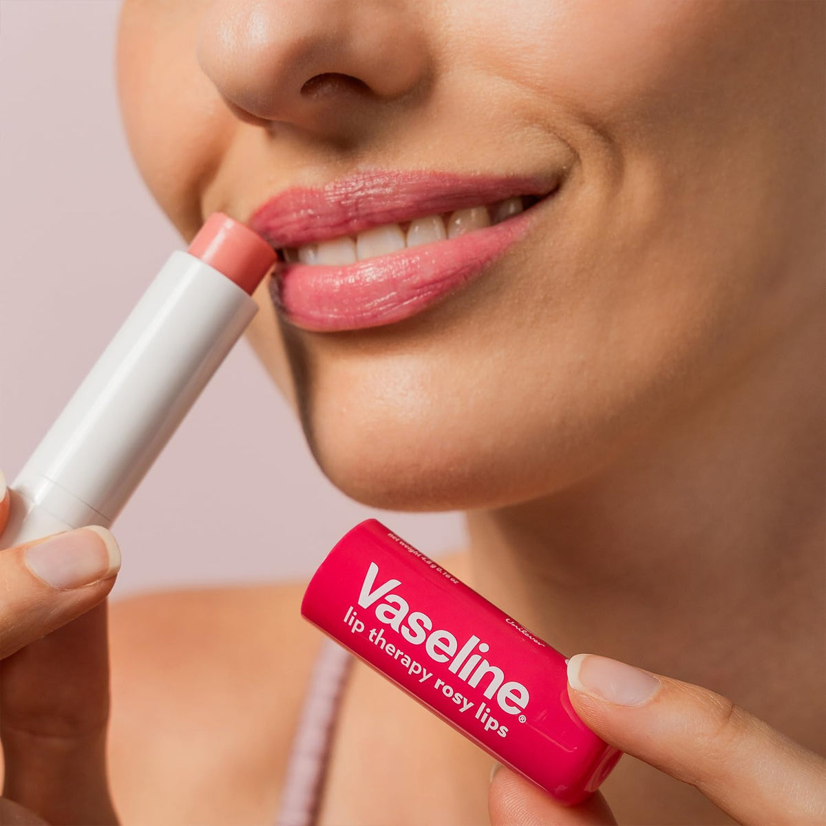 Vaseline rosy lips next to coin showing compact travel-size portability benefit