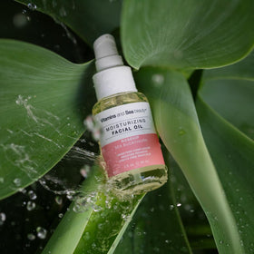 VITAMINS AND SEA BEAUTY next to a common-sized hand to show 2 fl oz scale
