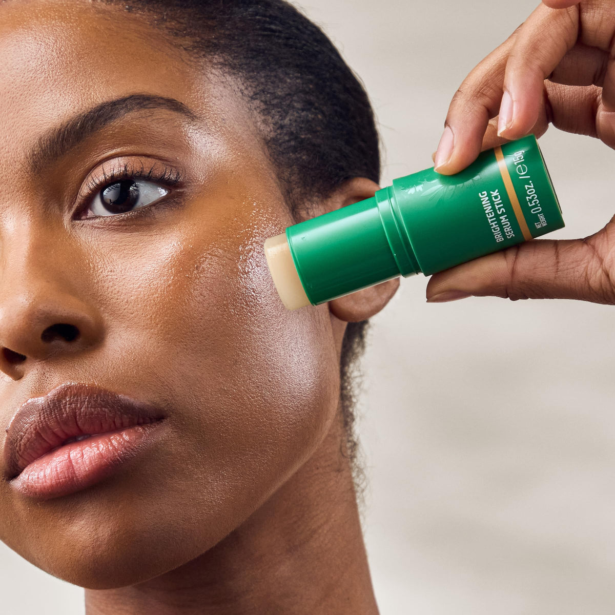 Model applying Weleda Skin Food stick to cheek for instant luminous boost