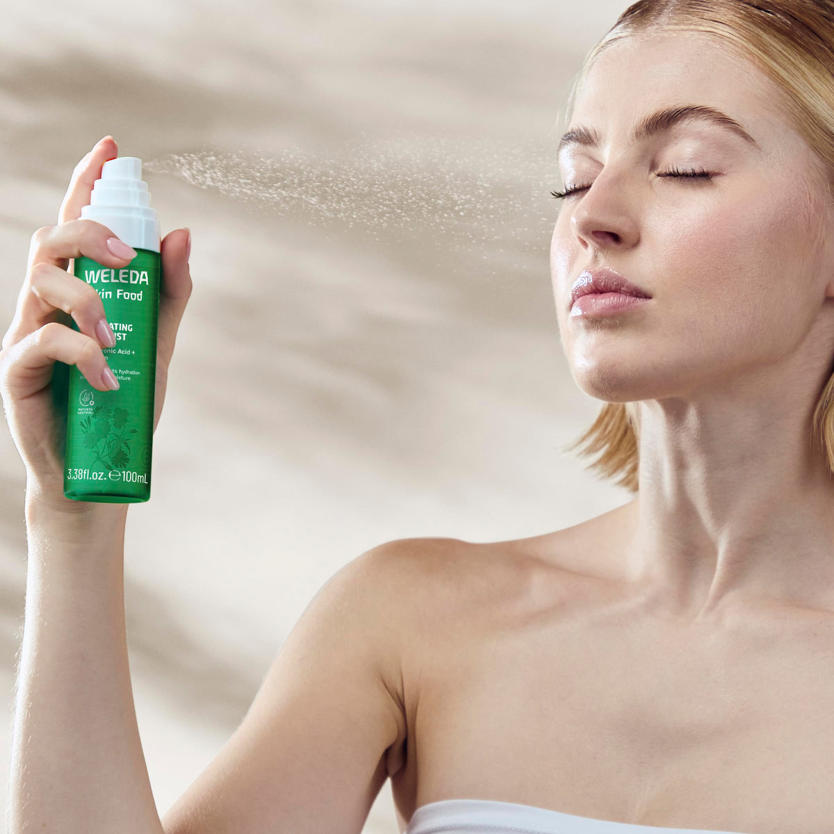 Weleda Skin Food mist size comparison in hand showing travel-ready, recycled packaging