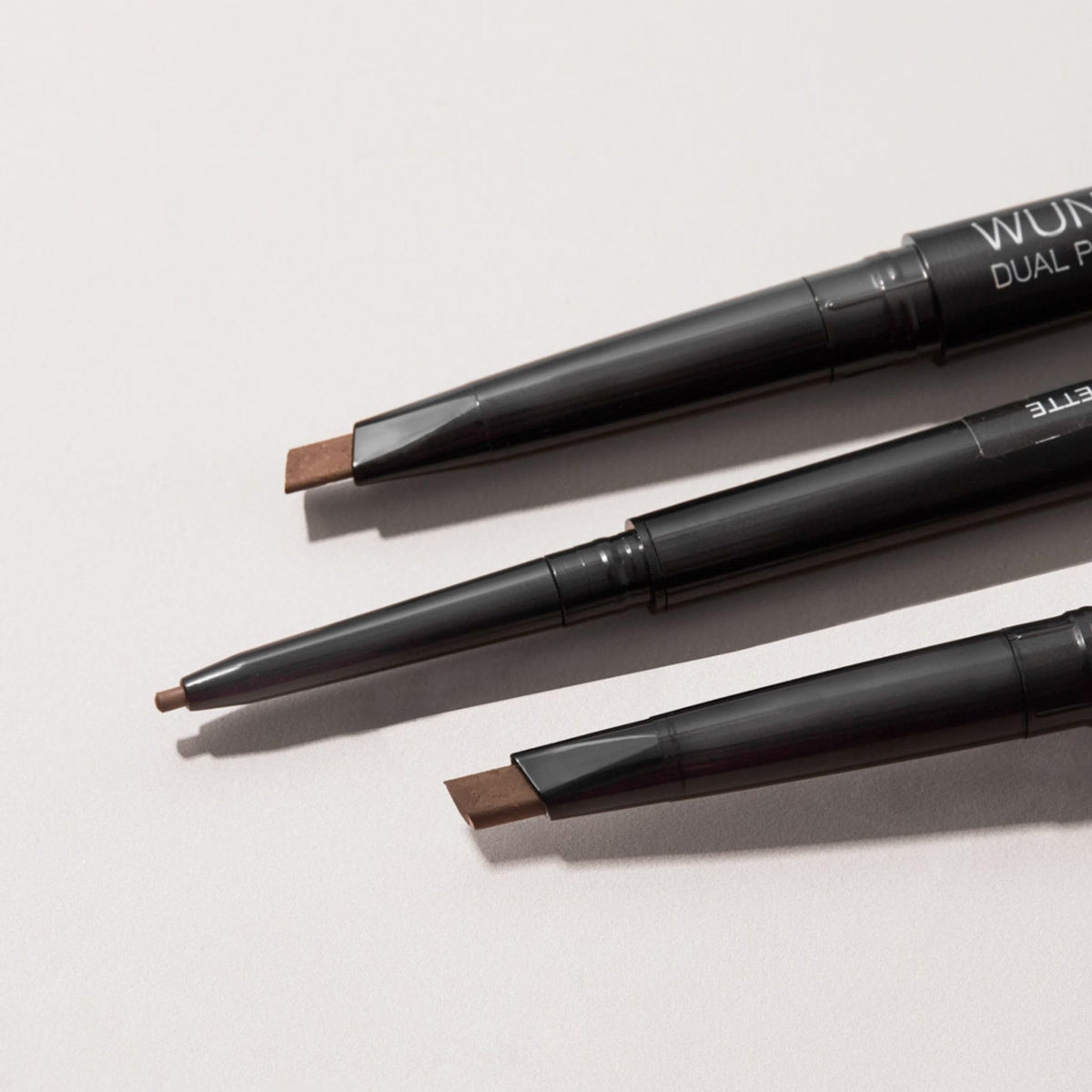 WUNDERBROW Brunette dual-ended pencil held for scale demonstrating travel convenience